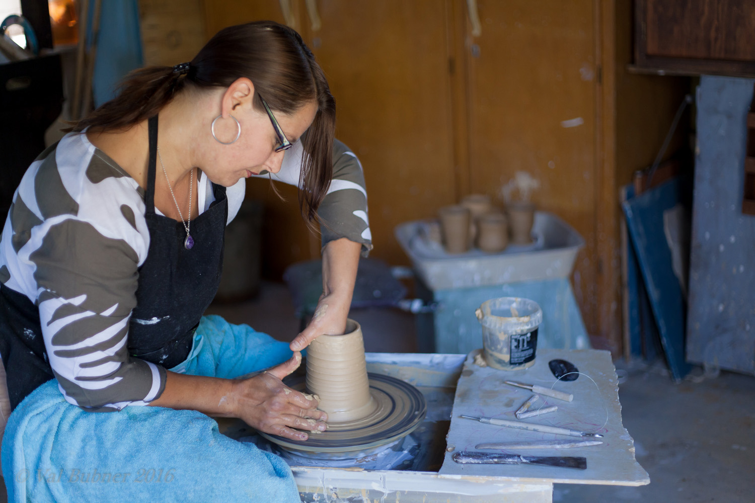 Tania Kunze a ceramic artist from Adelaide shaping a pot on the wheel in her studio